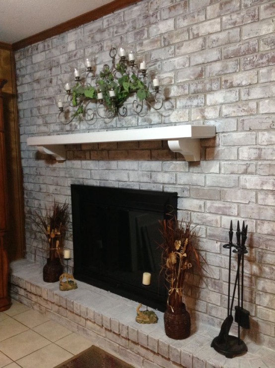 a built-in fireplace in a whitewashed brick wall, a mantel with greenery and candles, decorations around