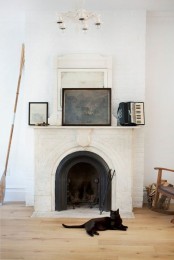 a whitewashed vintage fireplace clad with brick and plaster with a mantel with vintage items is a refined addition to your interior