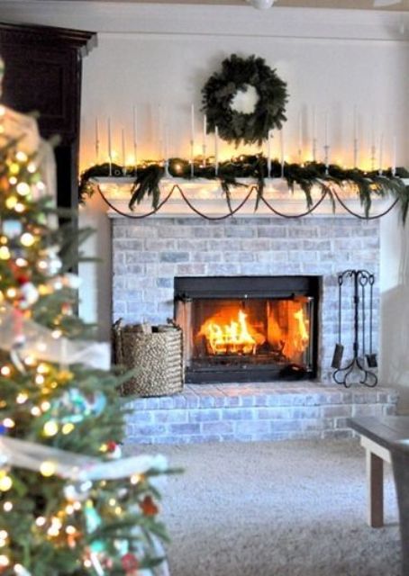 a whitewashed fireplace with a basket with firewood and a mantel decorated for Christmas