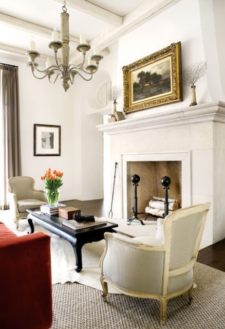 a large vintage whitewashed tile fireplace with firewood and a mantel plus a vintage artwork over it