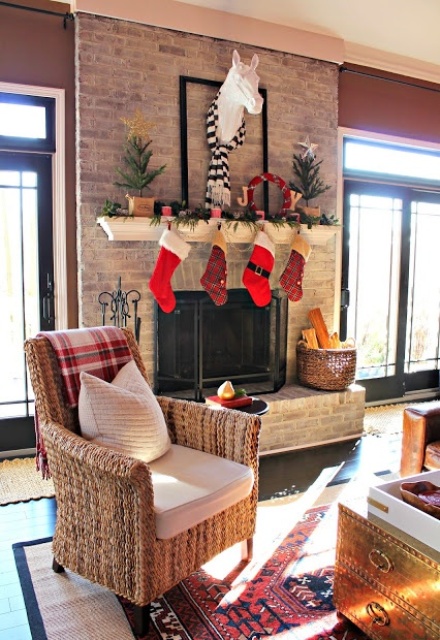 a whitewashed fireplace with a mantel decorated for Christmas and a basket with firewood is chic and cool