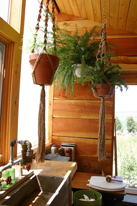 a rustic bathroom clad with warm-stained wood and with greenery in suspended planters that makes it closer to nature