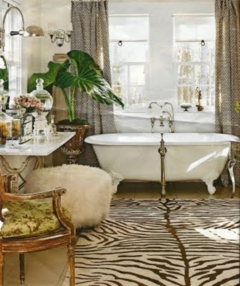 a quriky bathroom with a vintage tub, an animal skin rug, vintage furniture and a potted green plant for a statement