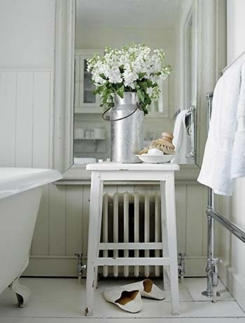 a white bathroom with fresh blooms in a metal jar that refresh the space and add a spring feel to it