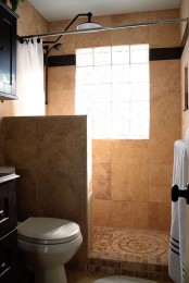 a warm-colored bathroom with a pony wall and sandy tiles, it’s small ye functional and feels airy thanks to the pony wall