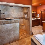a stylish bathroom with warm-colored walls, a shower space clad with grey tiles and with a half wlal to brign more light inside