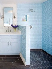 a blue bathroom with a navy tile floor in the shower, light blue tiles in the shower space and a light blue vanity is chic