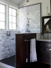 an elegant bathroom clad with marble subway tiles, with a dark half wall and a matching vintage vanity looks chic