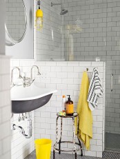 a mid-century modern bathroom clad with white subway tiles, with a half wall, a vintage sink and touches of yellow for a brighter look