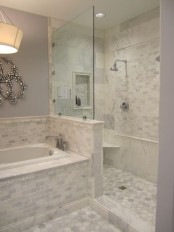 a romantic bathroom with lilac walls, marble tiles of various shapes and a pony wall in the shower space, a bathtub clad with tiles