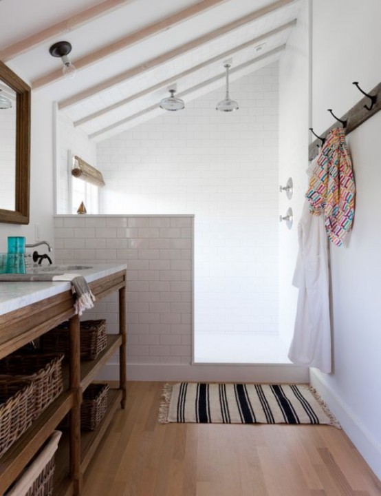 a neutral farmhouse bathroom clad with white subway tules and a pony wall that separates the shower from the rest of the space