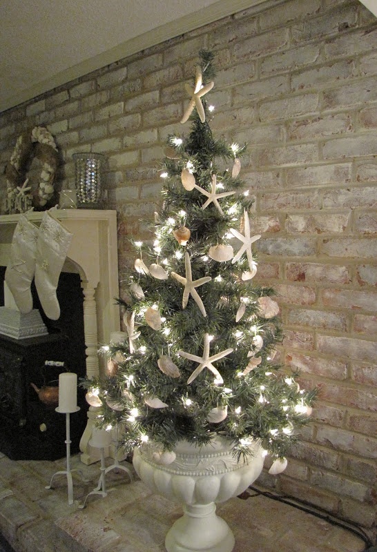 a white vintage urn with a Christmas tree, lights, seashells and starfish is a cool idea for a beach Christmas space