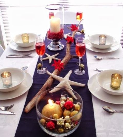a colorful beach Christmas tablescape with a navy runner, a driftwood piece, starfish, colorful ornaments in a bowl is a lovely idea