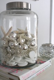 an oversized jar with seashells, silver ornaments, starfish and silver bottle cleaners is a lovely beach Christmas decoration