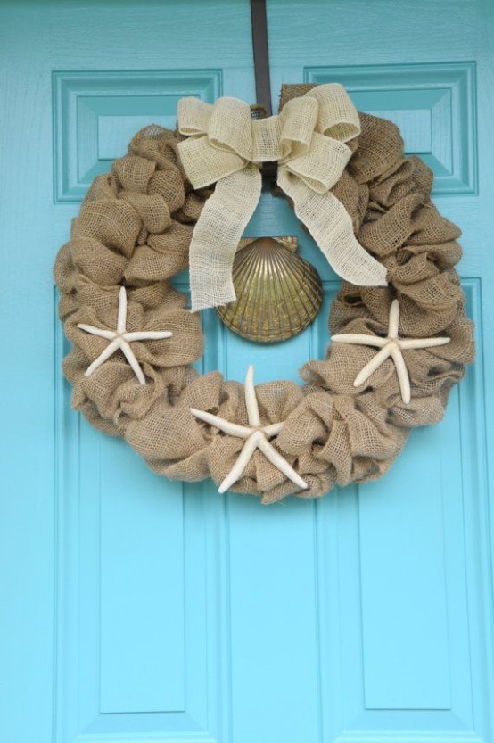 a burlap wreath with a white burlap bow on top and starfish is a cool idea for a rustic beach home at Christmas
