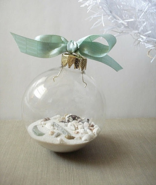 a clear Christmas ornament with beach sand and seashells plus a green ribbon bow is a great idea for Christmas, for a beach house