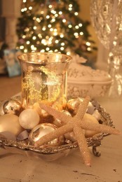 a beautiful Christmas centerpiece with white and pearly Christmas ornaments, a starfish and a mercury glass candle holder in the center
