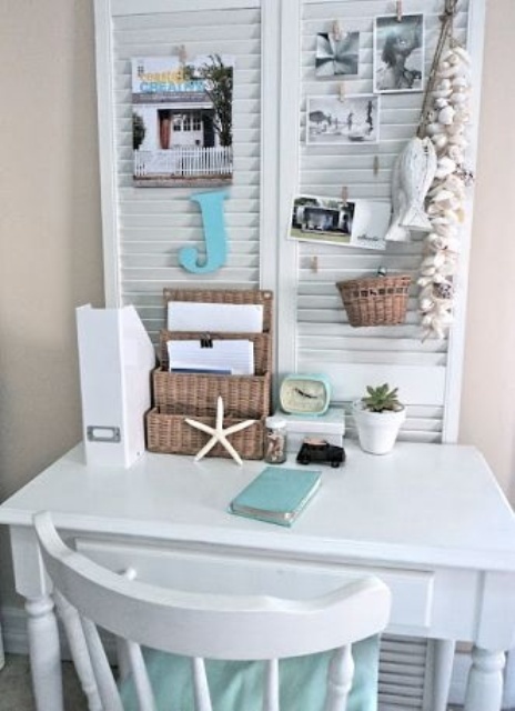 a beachy home office nook with a white desk and chair, with white shutters and various memos and photos on them