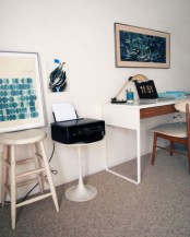 a coastal home office done in neutrals, with a desk, a a stand and a stool, with bold sea decor is amazing