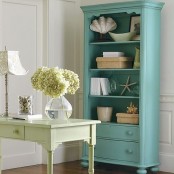 a  vintage-inspired beach home office with a green desk and a blue vintage storage unit feels elegant and looks chic