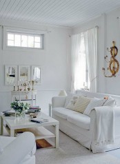 a modern white living room with much natural light, white seating furniture, a low coffee table, a delicate console table and some blooms is a chic space