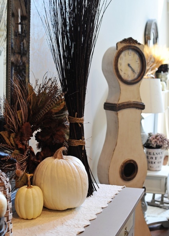 a chic fall arrangement of branches, several white pumpkins and a dried leaf and feather wreath