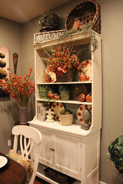 a bright arrangement of fall leaves, wheat and some orange pumpkins will give a rustic feel to the space