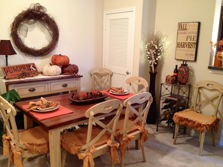 a stack of pumpkins, a vine wreath, a bowl with yarn balls and pinecones for fall decor