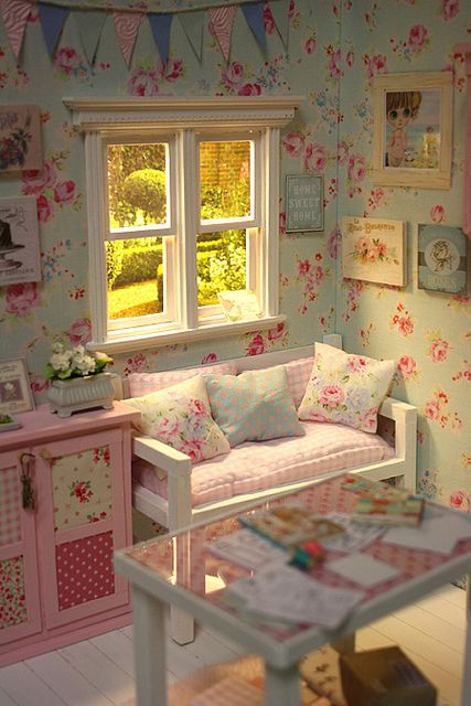 a pastel shabby chic kid's room with floral walls, pastel furniture, floral and plaid bedding, a colorful banner over the space