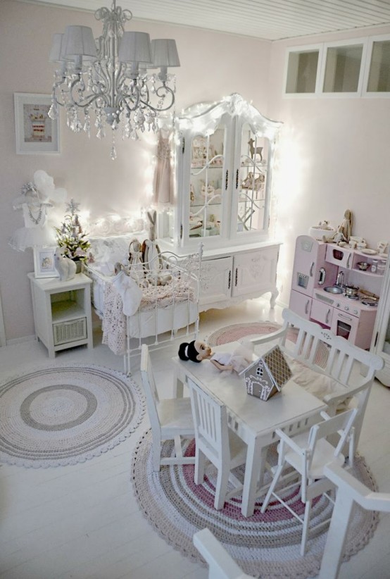a white shabby chic bedroom with refined white furniture, a pink play kitchen and a crystal chandelier and lights