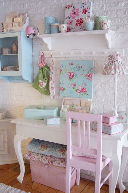 a shabby chic kid's room with white brick walls, beautiful white and pastel furniture, floral artworks and textiles and some other floral touches including lamps and artworks