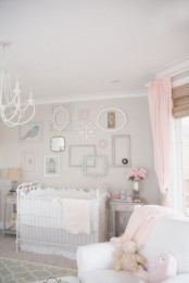 a pastel shabby chic bedroom with dove grey walls, a gallery wall of mirrors and empty frames, a white chandelier and pink textiles is very elegant