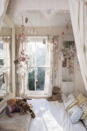 a neutral shabby chic kid’s room with a bed by the window, floral bedding and lots of vintage items hung over the bed as decor