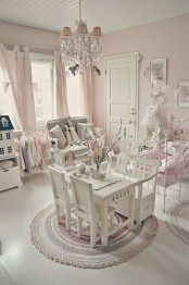 a pink and white vintage meets shabby kid’s room with elegant white furniture, a crystal chandelier, pink bedding and curtains, a pretty gallery wall