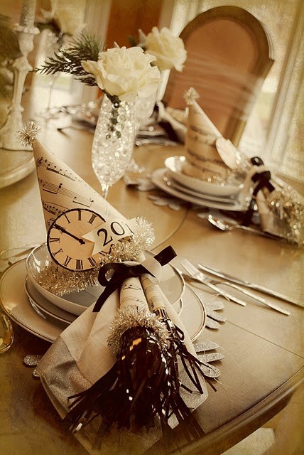 a neutral NYE party tablescape with snowflake placemats, white porcelain, cone hats and white roses and greenery is a chic idea
