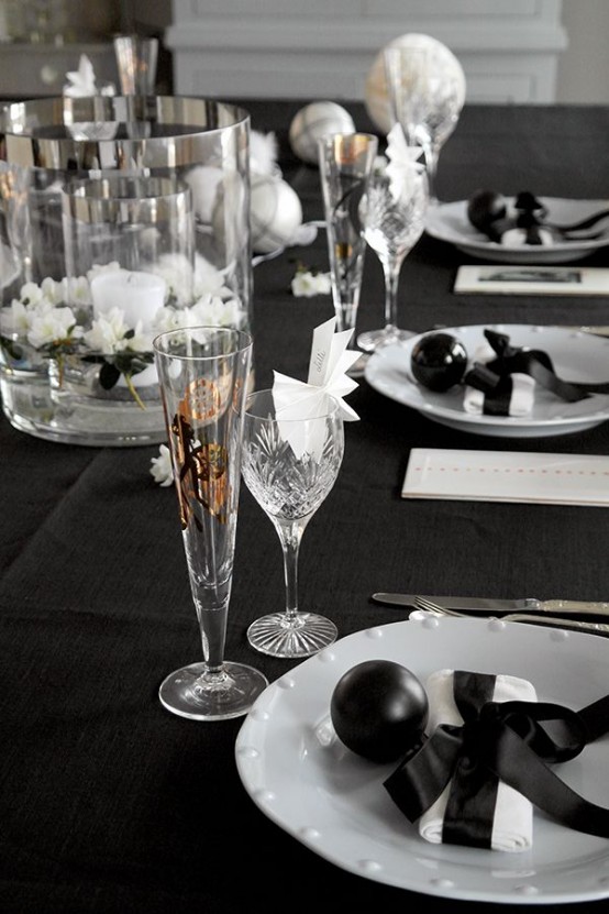 a laconic black and white NYE tablescape with glasses and white blooms, white porcelain, crystal glasses and gold printed ones is chic