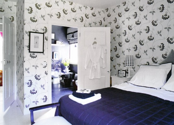 a dark blue, creamy and white bedroom wiht a grey bed and bold bedding