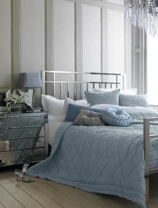 a grey bedroom with a silver finish bed, a mirror nightstand and blue and grey bedding