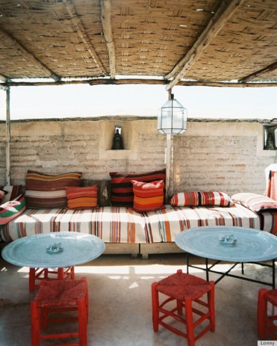 a welcoming boho patio done with blue and reds, with lots of stripes and candle lanterns