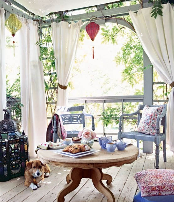 a boho patio with colorful paper lanterns and an oversized mosaic lantern, floral pillows and light blue furniture
