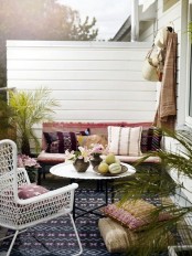 a welcoming boho patio with a mosaic floor, printed pillows and rugs, potted greenery and a wicker chair