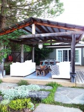 a rustic patio with white sofas, a dining space, printed textiles and a dark stained roof