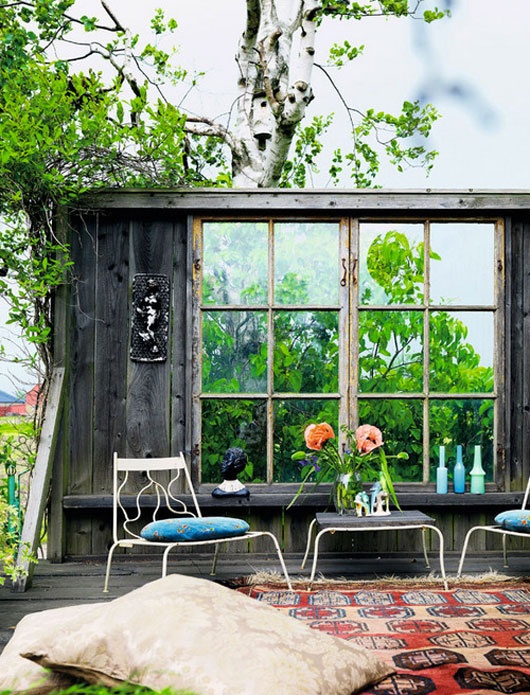 a bright and open boho patio with rugs, pillows, cushions and bright bottles and ottomans
