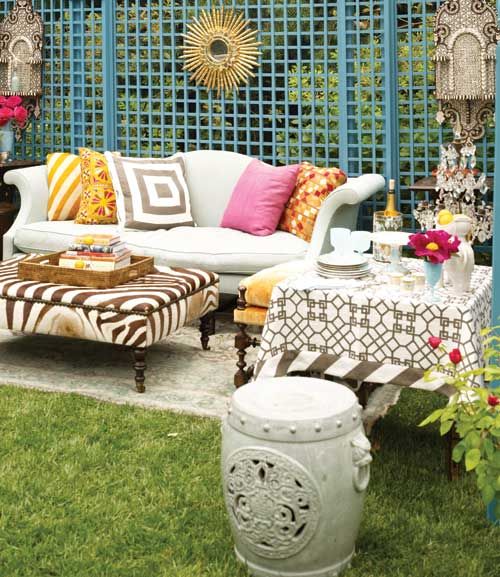 a colorful boho patio with a blue screen, bright printed pillows, Moroccan lanterns and a printed ottoman