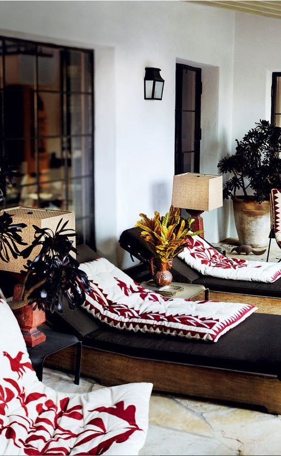 a bright boho patio with black loungers, printed pillows, burlap lamps and potted greenery