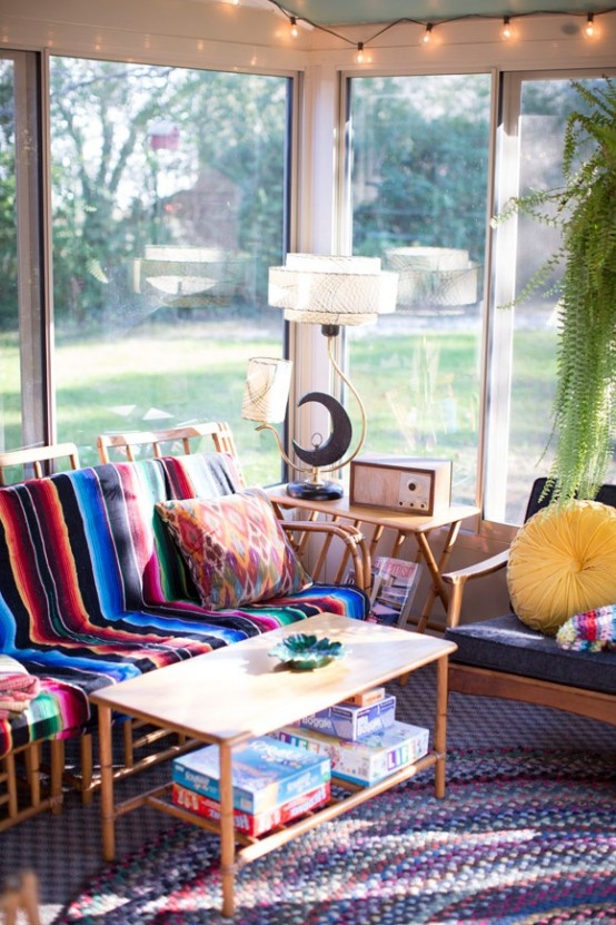 a colorful boho and mid-century sunroom with a cool view, with furniture with bright textiles, pillows, rugs and some pretty potted plants is a cozy and cool space