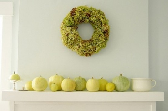 a modern rustic mantel decorated with a green hydrangeas wreath and natural white, green and yellow pumpkins
