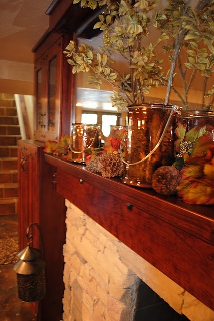 a rustic fall mantel decorated with pinecones, leaves and branches in a vase for a cozy feel