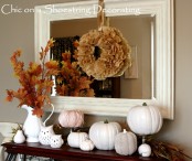 a vintage fall mantel decoarated with faux pumpkins in white, fall leaves, owls and a paper pompom wreath