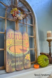 a vintage rustic fall mantel with a vintage sign, faux pumpkins, candles and a vinte wreath with twigs and fabric blooms